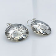 Sterling-Silver-Floral-Textured-Domed-Medallion-Earrings laying diagonal